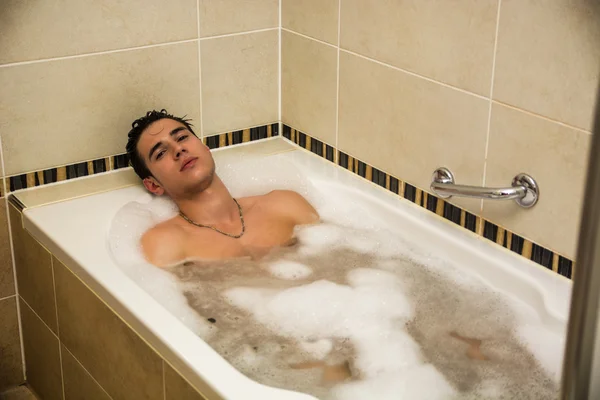 Guapo joven en la bañera en casa teniendo baño —  Fotos de Stock