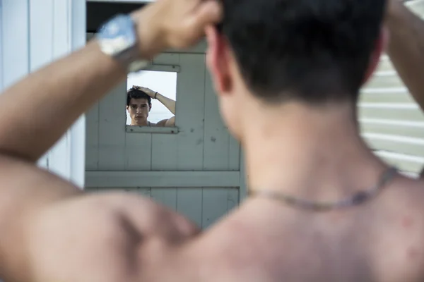 Hombre joven parado en la puerta de la choza de playa rústico — Foto de Stock