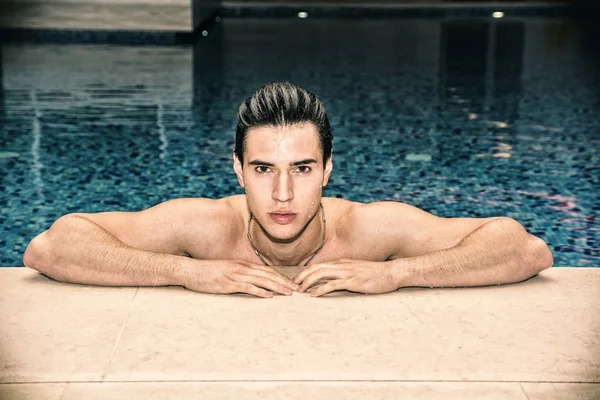 Homem jovem relaxante na piscina — Fotografia de Stock