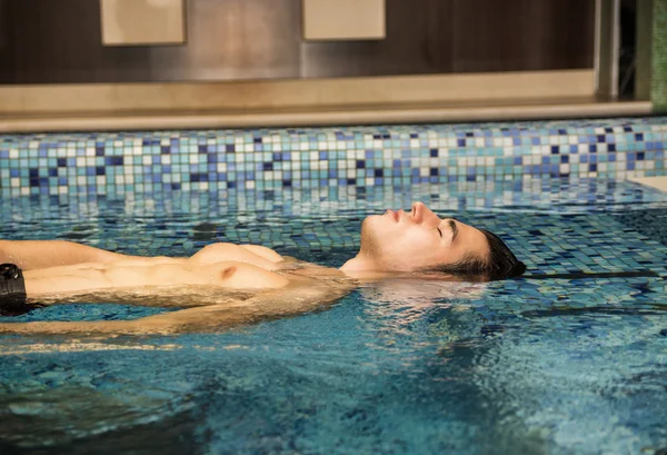 Homem jovem relaxante na piscina — Fotografia de Stock