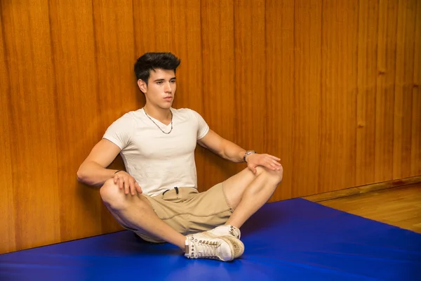 Handsome young man stretching on gym mat — Stock Photo, Image