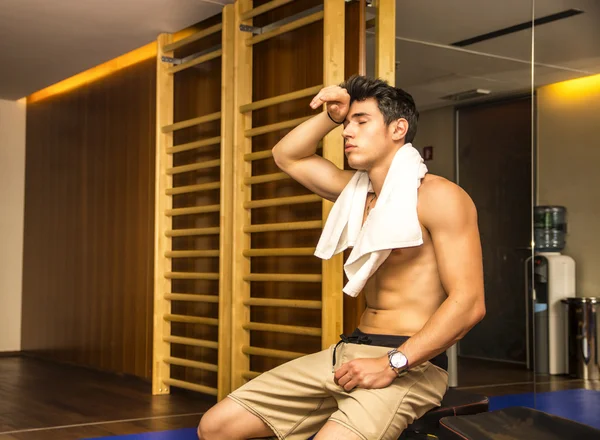 Muscular shirtless male athlete drying sweat with towel