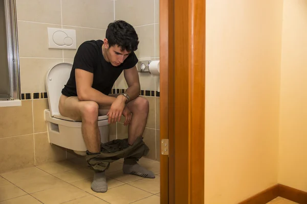 Jeune homme assis sur les toilettes — Photo