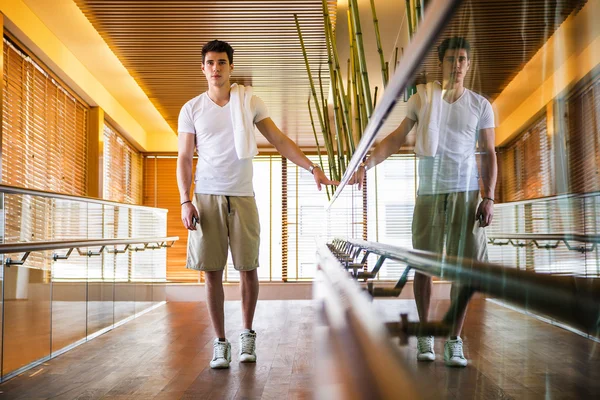 Ung Man stående i hallen håller ledstång — Stockfoto