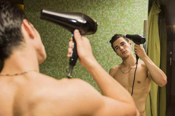 Jeune homme torse nu séchant les cheveux avec sèche-cheveux — Photo