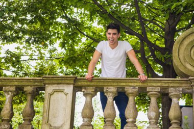 Handsome young man standing on a balcony or bridge