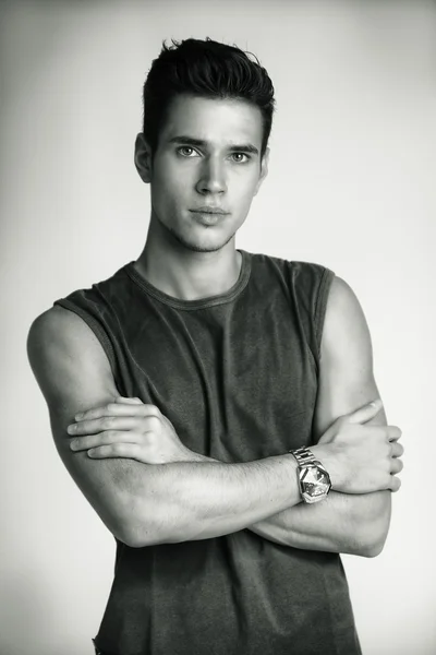 Serious looking young man wearing sleeveless shirt looking at camera — Stock Photo, Image