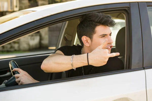 Giovane che guida un'auto e mostrando il dito medio — Foto Stock