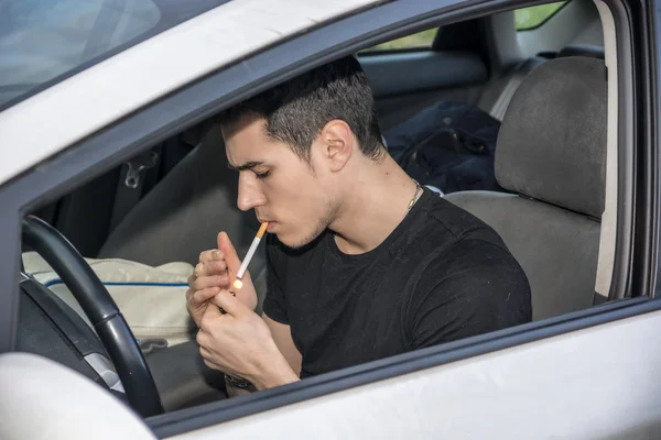 Hombre joven fumando cigarrillo mientras conduce —  Fotos de Stock