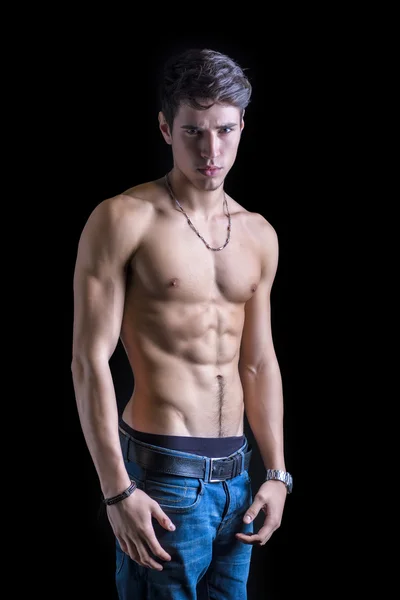 Handsome, fit shirtless young man in jeans isolated on black — Stok fotoğraf