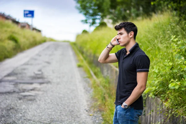 Молодой человек на обочине дороги, вызывной и ждет такси — стоковое фото
