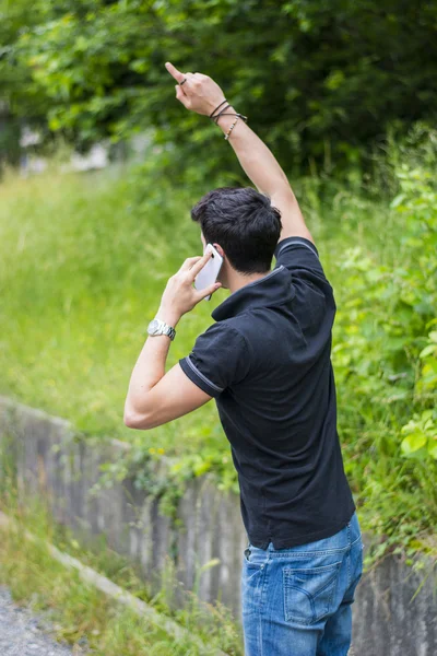 Jeune homme sur le côté d'une route, en appelant et en attente pour le taxi — Photo