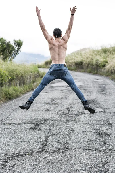 Back of shirtless fit young man jumping for joy — Stok fotoğraf