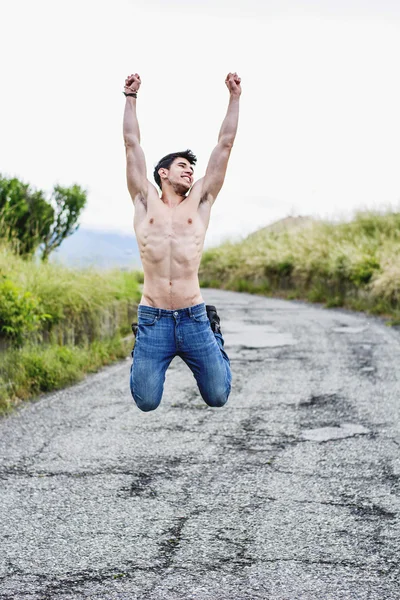 Giovane uomo muscolare senza camicia saltando per la gioia — Foto Stock