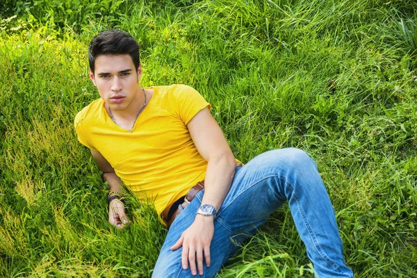 Dopasowanie przystojny młodzieniec, relaksujący, leżąc na trawie trawnik — Zdjęcie stockowe
