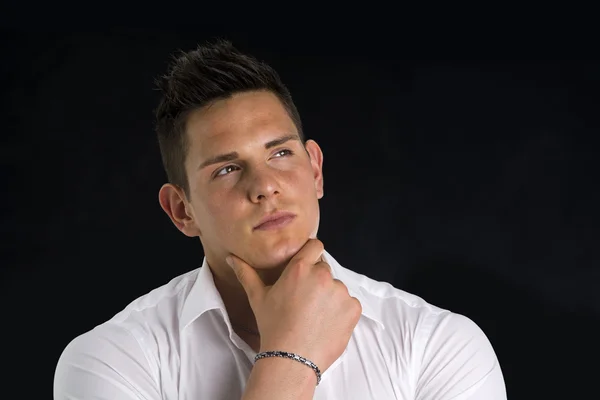 Attractive young man thinking, looking up with hand on his chin — Stock Photo, Image