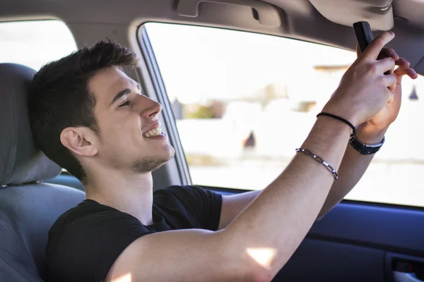 Gut aussehender junger Mann im Gespräch Selfie in einem Auto — Stockfoto