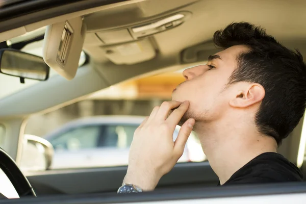 Homme regardant son Pimple Utilisation Miroir d'une voiture — Photo