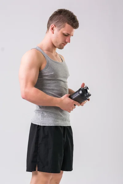 Jovem atraente segurando garrafa de batido de proteína — Fotografia de Stock