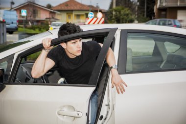 Young man getting out of white car