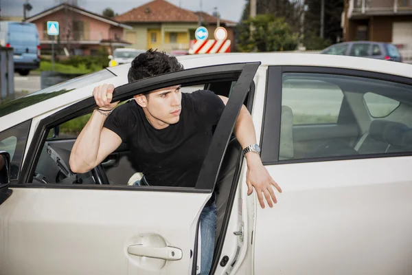 Young man getting out of white car — Stockfoto