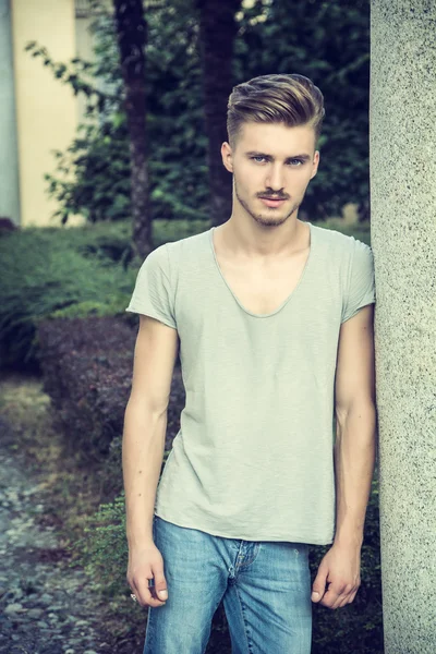 Handsome young man standing outdoors under old colonnade — Stock Photo, Image