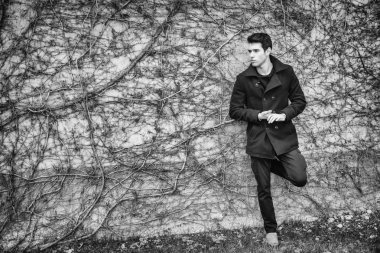 Yakışıklı genç adam kapalı bitki duvara karşı ayakta