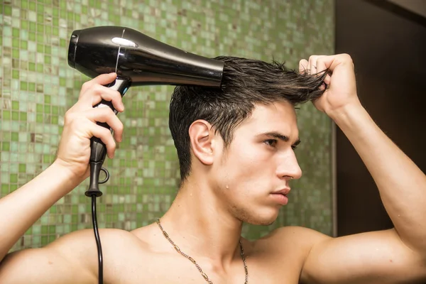 Jovem sem camisa secando o cabelo com secador de cabelo — Fotografia de Stock