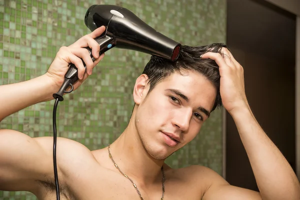 Hombre joven sin camisa secando el cabello con secador de pelo — Foto de Stock