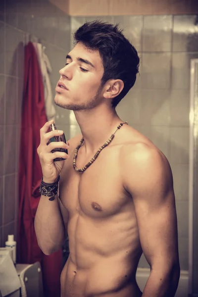 Handsome young man in bathroom, spraying cologne or perfume — Stock Photo, Image