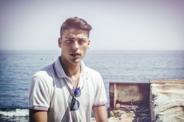 Handsome young man sitting next to the sea