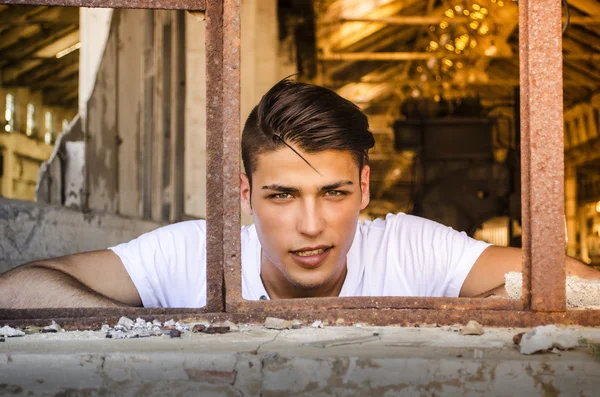 Handsome young man with happy expression in rusty window — ストック写真