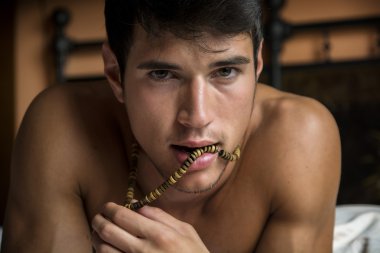 Tişörtsüz seksi erkek model yatağında tek başına yatıyor.