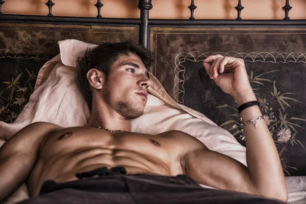 Shirtless sexy modelo masculino deitado sozinho em sua cama — Fotografia de Stock