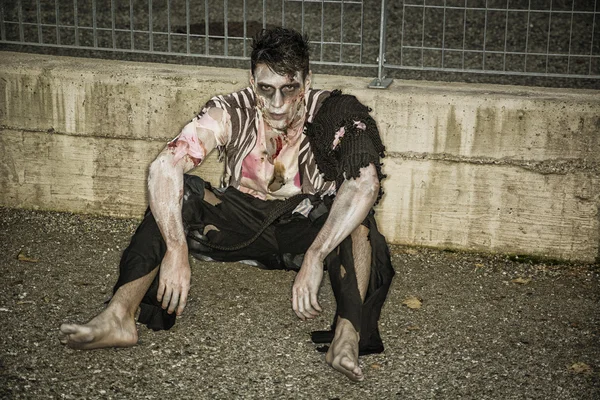 Jeden zombie mężczyzna siedzi w puste miasto ulica na Halloween — Zdjęcie stockowe