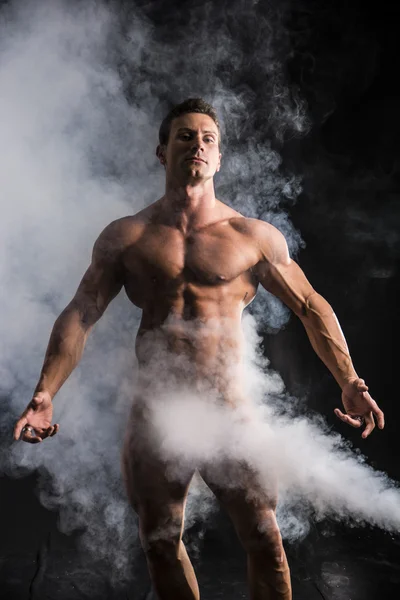 Totally naked male bodybuilder with smoke hiding genitalia — Stock Photo, Image