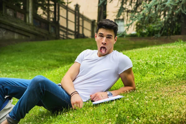 Молодой мужчина студент делает глупое лицо в городском парке — стоковое фото