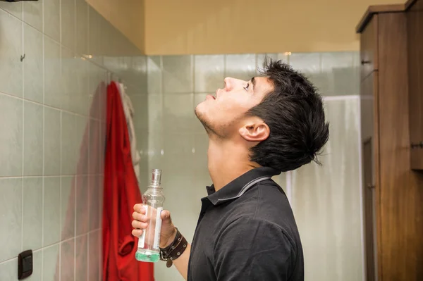 Gut aussehender junger Mann mit Mundwasser, im Badezimmer — Stockfoto