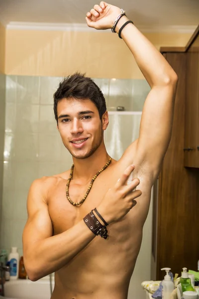 Yakışıklı bir genç adam banyoda, Köln veya parfüm püskürtme — Stok fotoğraf