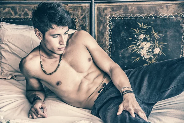 Сексуальный мужчина без рубашки лежал один на кровати — стоковое фото