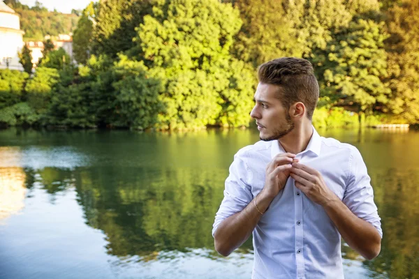 Contemplatieve jonge man zit naast de rivier — Stockfoto