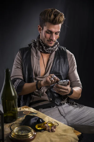 Pirate Man met mobiele telefoon zitten door tabel — Stockfoto