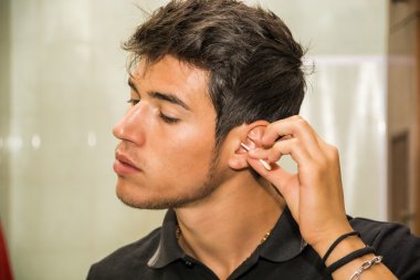 Young Man Cleaning Ears with Cotton Swab