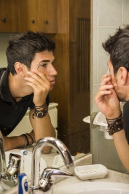 Reflection of Young Man Plucking Eyebrow Hairs