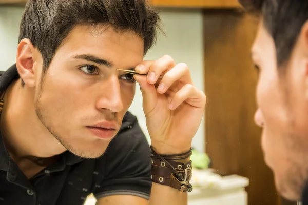 Reflexion der jungen Mann zupfen Augenbrauen-Haare — Stockfoto