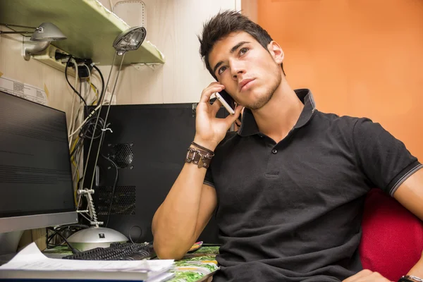 Young Man Talking on Cell Phone at Computer Desk — Foto Stock
