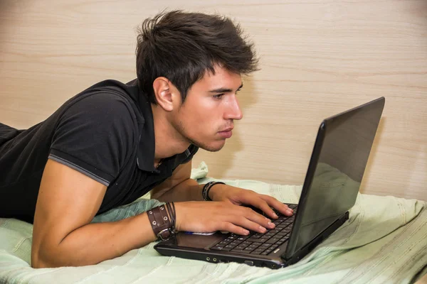 Jovem fazendo lição de casa no laptop no quarto — Fotografia de Stock