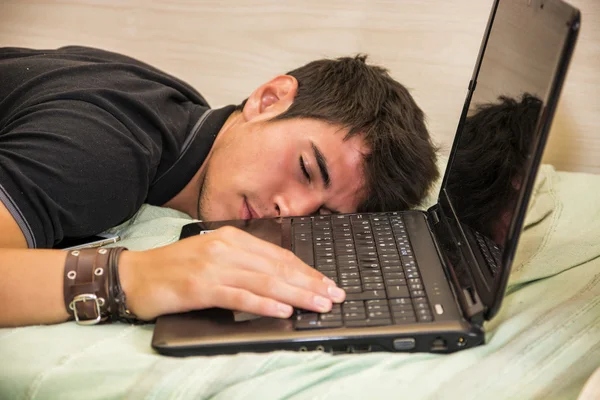 Уставший молодой человек спит на следующем ноутбуке — стоковое фото