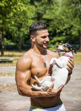 Onun kollarında köpekle gömleksiz atletik erkek