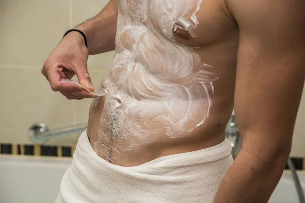 Young man shaving hair from stomach and chest. — Stock Photo, Image